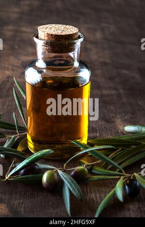 Bouteille d'huile d'olive extra vierge à côté de quelques olives sur leurs branches. Banque D'Images