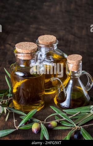 Bouteille d'huile d'olive extra vierge à côté de quelques olives sur leurs branches. Banque D'Images