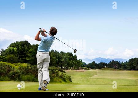 Un jeune golfeur se présente au parcours de golf de Kilmarnock Barassie, en 17th, avec vue sur les collines de l'île d'Arran au loin, Troon, Ayrshire Banque D'Images