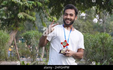 jeune enfant indien, garçon d'école tenant une médaille d'or et une coupe de trophée Banque D'Images