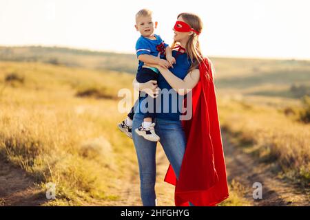 Bonne famille aimante.Maman et son fils jouent à l'extérieur.Maman et son enfant en costumes de super-héros.Concept de fête des mères, mars 8 Banque D'Images