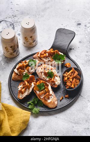 Sandwichs chanterelle au fromage. Sandwich ouvert avec fromage crémeux, assaisonnements, poivre et persil frais sur un fond de bois ancien. Faux Banque D'Images