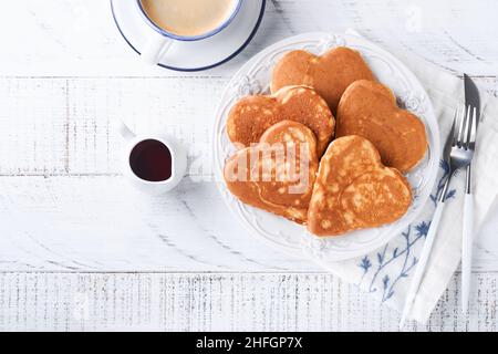 Crêpes avec confiture de baies et miel en forme de coeur et une tasse de café chaud sur fond de bois blanc.Petit déjeuner concept pour la Saint Valentin ou le plaisir Banque D'Images