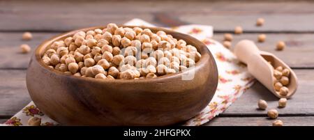 Pois chiches non cuits dans une assiette de bambou sur fond de table en bois.Mise au point sélective. Banque D'Images