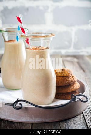 Smoothies à la vanille au lait et biscuits aux flocons d'avoine dans des pots en verre sur fond de bois ancien.Mise au point sélective. Banque D'Images