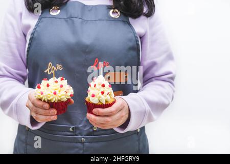 Serveuse avec deux cupcakes décorés avec des coeurs rouges et une enseigne en bois avec des lettres D'AMOUR.Concept de la Saint-Valentin et de la fête des mères.Blanc Banque D'Images