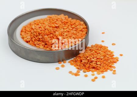 Lentilles rouges non cuites dispersées sur une surface blanche Banque D'Images