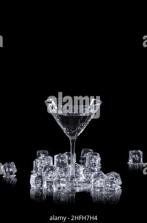 un verre martini entouré de glaçons sur un arrière-plan réfléchissant noir, avec espace de copie Banque D'Images