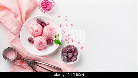 Trois boules de crème glacée avec des cerises et des coeurs congelés sur fond blanc.Vue de dessus, espace de copie. Banque D'Images