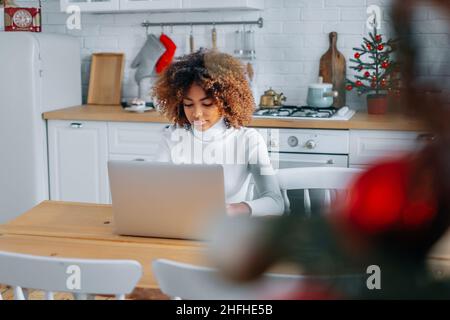 Jeune acheteur à la peau sombre et excitée avec des cheveux tendance dans les sourires d'ordinateur portable et aime faire du shopping en ligne à proximité Banque D'Images