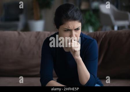 Une jeune femme indienne malsaine tousse à la maison. Banque D'Images