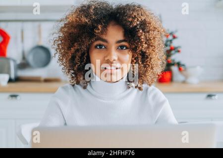 Jeune acheteur à la peau sombre et excitée avec des cheveux tendance dans les sourires d'ordinateur portable et aime faire du shopping en ligne à proximité Banque D'Images