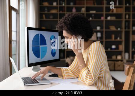Femme d'affaires afro-américaine concentrée multitâche dans un bureau moderne. Banque D'Images