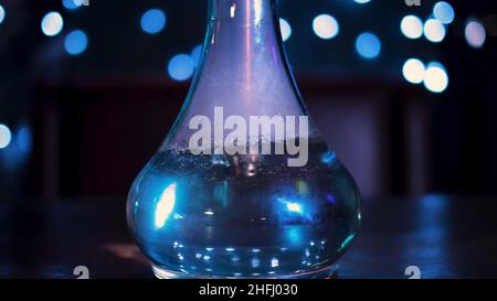Fumer le nargua sur une table sombre, dans les nuages de fumée et de lumière.Flacon en verre avec liquide violet sur fond noir fumé.Shisha oriental élégant c Banque D'Images