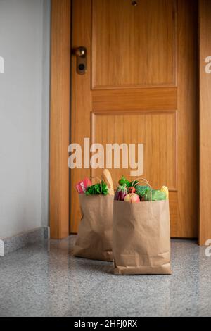 Des sacs de shopping de nourriture sont à la porte de la maison ou de l'appartement.Livraison de légumes et de fruits pendant la quarantaine et l'auto-isolement. Banque D'Images