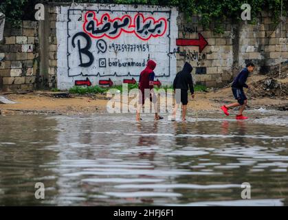 Gaza, Palestine.16th janvier 2022.Des enfants palestiniens ont traversé une route inondée à la suite de fortes pluies dans le nord de la bande de Gaza.(Photo de Mahmoud Issa/SOPA Images/Sipa USA) crédit: SIPA USA/Alay Live News Banque D'Images