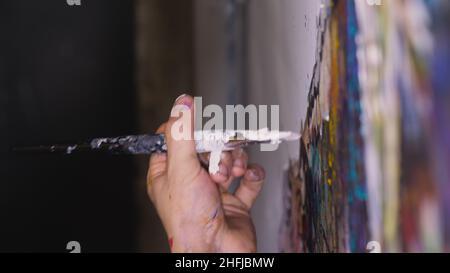 Un artiste designer dessine un aigle sur le mur.Artisan décorateur peint une image avec de l'huile acrylique couleur.Gros plan, magie et obscurité, aspect cinématographique. Banque D'Images