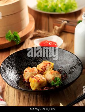 Boulettes de Shumai asiatique à l'huile de Chili rouge, graines de sésame et persil et verts frais.Chinois traditionnel Dim Sum Tuletas. Banque D'Images