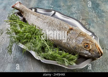 Poisson-bar frais avec herbes sur la planche, prêt à cuire.Cuisine gastronomique française Banque D'Images