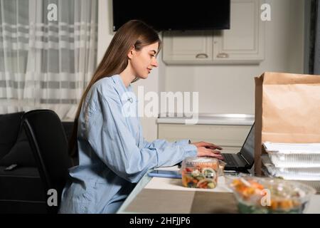 Concept de livraison de nourriture à domicile.Femme à la table avec des récipients jetables de nourriture saine pour la perte de poids.Achats en ligne.Livraison des commandes au restaurant. Banque D'Images