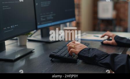 Gros plan des mains du développeur en tapant du code sur le clavier tout en regardant les écrans d'ordinateur avec interface de programmation.Programmeur de logiciel assis à un bureau avec un algorithme d'écriture de presse-papiers. Banque D'Images