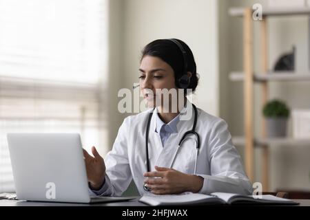 Bonne jeune femme médecin indien tenant une conversation par appel vidéo. Banque D'Images