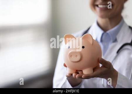 Gros plan jeune médecin indien tenant la porcgybank entre les mains. Banque D'Images