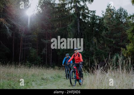 Couple senior actif à vélo en plein air dans la forêt en automne. Banque D'Images