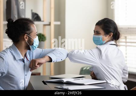 Un jeune patient afro-américain heureux touche les coudes avec un médecin indien. Banque D'Images