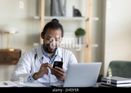 Souriant jeune médecin afro-américain utilisant un téléphone portable. Banque D'Images