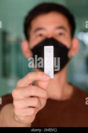 Un homme détenant un résultat de test négatif Covid-19 avec un kit de test rapide d'antigène (ATK) Banque D'Images