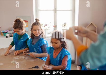 Groupe de petits enfants travaillant avec de l'argile poterie pendant la création artistique et cours d'artisanat à l'école. Banque D'Images