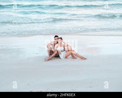 Bel homme et jolie femme assis sur la plage Banque D'Images