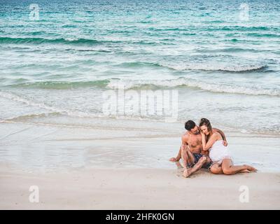 Bel homme et jolie femme assis sur la plage Banque D'Images