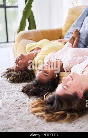 Photo verticale d'une femme d'amitié souriante au sofa.Les jeunes s'amusent ensemble à la maison. Banque D'Images