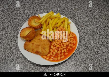 Une vue de haut en bas d'un repas de schnitzel, chips, haricots cuits et Yorkshire puddings. Banque D'Images