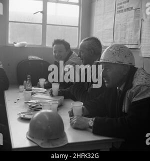 Aéroport de Heathrow, BEA Servicing Hangar, Heathrow, Hillingdon, Londres,07/04/1970.Trois ouvriers de Laing assis à une table après un repas dans la cantine du site pendant la construction de l'avion BEA desservant le hangar à l'aéroport d'Heathrow.En octobre 1969, Laing a annoncé que sa succursale de génie industriel avait obtenu un contrat pour la construction d'un avion desservant le hangar de British European Airways à l'aéroport d'Heathrow.Il s'agissait x2019 du deuxième contrat majeur de l'entreprise à Heathrow, après l'achèvement du terminal de fret BEA et BOAC. Banque D'Images