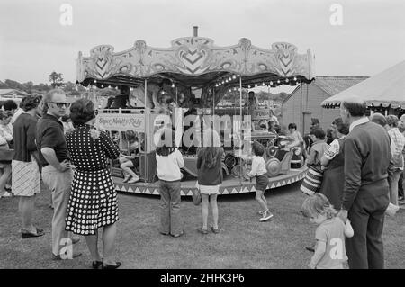 Laing Sports Ground, Rowley Lane, Elstree, Barnett, Londres,09/06/1973.Personnes se tenant autour d'un carrousel pour enfants lors du Gala Day annuel qui a lieu au Laing Sports Ground à Elstree.Le Gala annuel a eu lieu au Laing Sports Ground le 9th juin 1973.Parmi les attractions, mentionnons des démonstrations de chiens de police, des avions modèles, le groupe de la Royal British Legion, des courses pour enfants et des sports.Le soir, il y avait de la danse et du bingo dans le Club House, et "bière et beat" dans le chapiteau.Plus de 2 000 personnes ont assisté au gala, et plus de 600 personnes ont séjourné pour le spectacle du soir. Banque D'Images