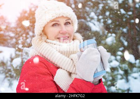 Portrait d'une femme tenant une tasse thermo dans une forêt enneigée d'hiver Banque D'Images