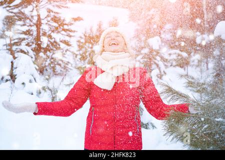 La femme heureuse attrape des flocons de neige pour la photo dans la forêt d'hiver Banque D'Images