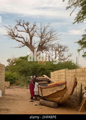 Sénégal, Afrique - 24 janvier 2019 : un énorme baobab et un bateau en bois sur la route rouge africaine.Arbre du bonheur, Sénégal.Afrique. Banque D'Images