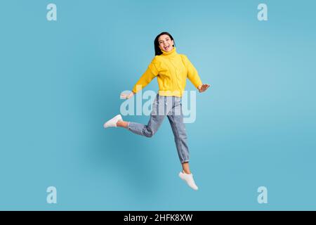 Photo de côté pleine longueur de la taille du corps de brunette sautant haut riant surjoyé isolé sur fond bleu vif Banque D'Images