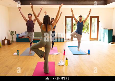 Professeur de yoga montrant l'exercice de yoga aux hommes et aux femmes multiraciaux dans le studio de yoga Banque D'Images