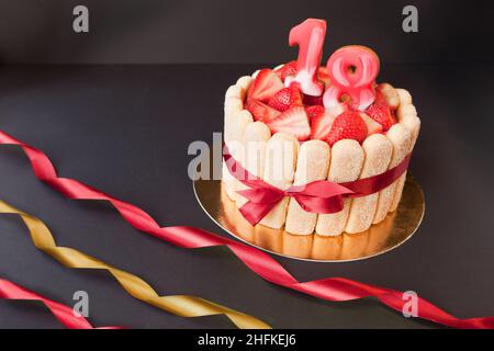 fête d'anniversaire 18. gâteau de tiramisu fraise sur fond noir avec ruban.Concentrez-vous sur les fraises. Banque D'Images