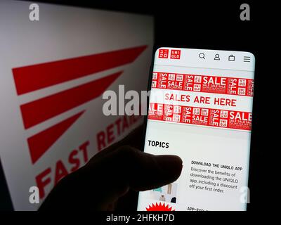 Personne détenant un smartphone avec la page Web Uniqlo de la société japonaise de vente au détail K.K.Vente rapide à l'écran avec logo.Concentrez-vous sur le centre de l'écran du téléphone. Banque D'Images