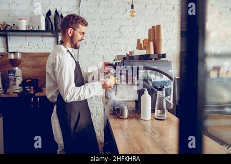 Un barista souriant utilise une machine à café dans le café Banque D'Images