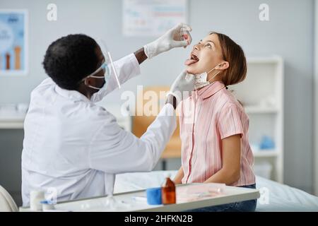 Portrait afro-américain d'un médecin qui dépose du liquide dans la bouche de l'enfant pendant la vaccination orale en clinique Banque D'Images