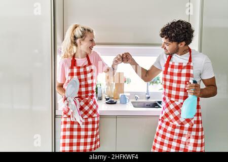 Un jeune couple souriant des plats de lavage heureux bump poings à la cuisine. Banque D'Images