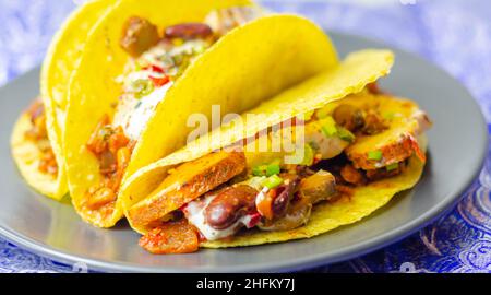 Coquilles de tacos mexicaines avec haricots rouges et de poulet, oignons, poivrons rouges et verts, sauce salsa, nourriture latine Banque D'Images