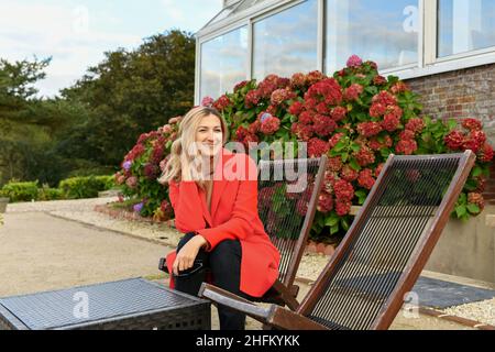 Une fille au pelage rouge se trouve dans un café sur la terrasse près de l'hortensia Banque D'Images